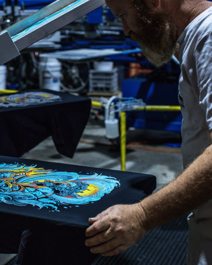 Hand-printed Project Poseidon artwork by Minnie Longstaff, screenprinted using Union Ink’s UPLC UNI MIX range supplied by Avient. Printed by BlackDog Ink on an M&R press, with garments supported by AS Colour. Materials supplied by Jones Brothers in Melbourne, Australia. Professional screenprinting process photo.