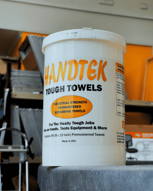 Tekmar HandTek Tough Towels container sitting on a screenprinting workbench in Melbourne, Australia, showing heavy-duty industrial wipes used for cleaning ink, adhesives and equipment in a professional screenprinting shop.
