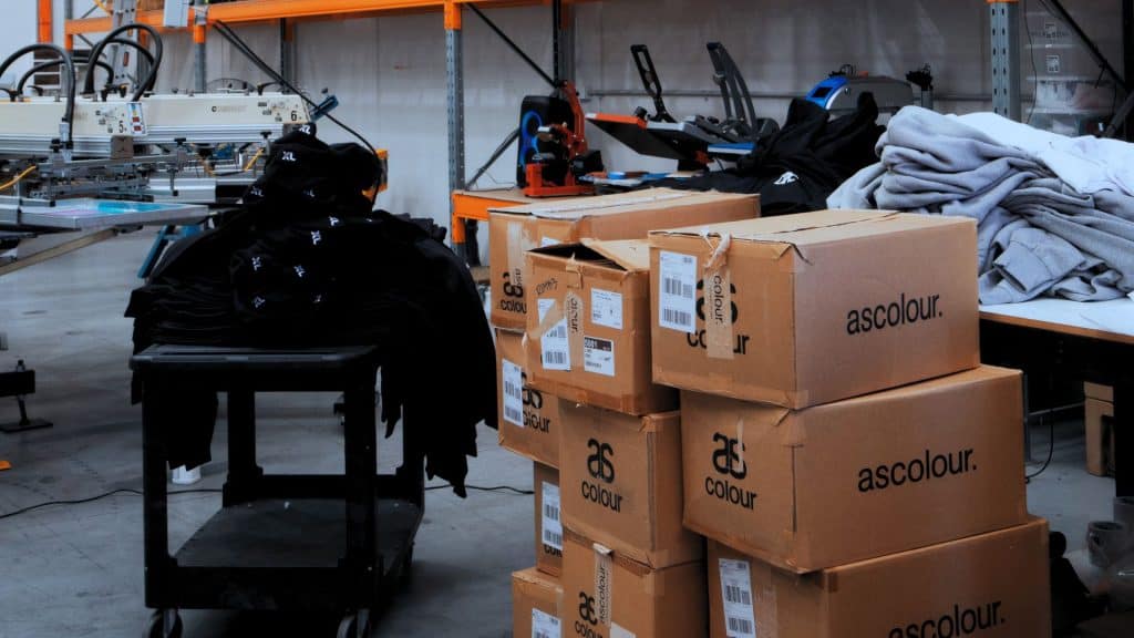Chris Benson, self-taught screen printer and owner of Cherry Studios, pictured in his production space with screens and equipment behind him—capturing the hustle, growth and authenticity described in the Behind the Mesh December 2025 interview.