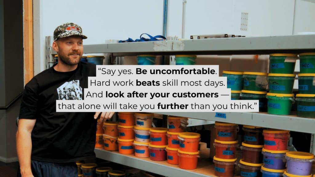 Chris Benson, self-taught screen printer and owner of Cherry Studios, pictured in his production space with screens and equipment behind him—capturing the hustle, growth and authenticity described in the Behind the Mesh December 2025 interview.
